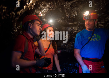 Tourists exploring the underground caves created by lava in the Grand Brûlé. Cooling and crystallization of basaltic lava around Stock Photo