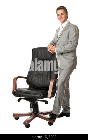Handsome young man standing next to an armchair Stock Photo