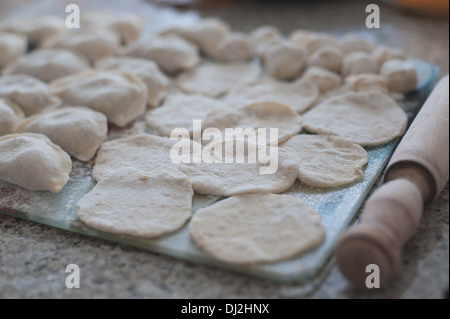 An image of raw dumplings and pieces of dumplings on the board Stock Photo