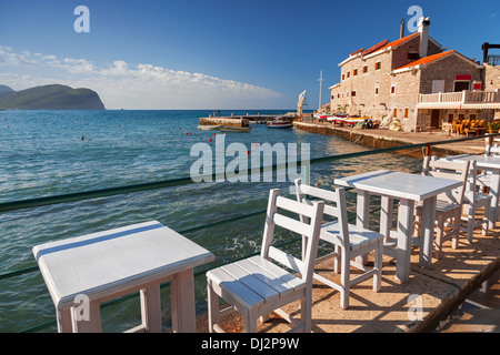 White wooden chairs and tables stand on Adriatic sea coast in Petrovac, Montenegro Stock Photo