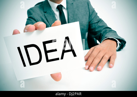 man wearing a suit sitting in a table showing a signboard with the word idea written in it Stock Photo