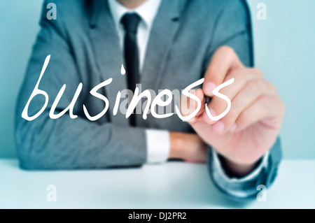 man wearing a suit sitting in a table writing the word business in the foreground Stock Photo