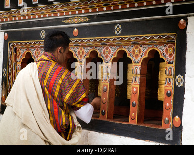 Bhutan, Thimpu Dzong, devotee spinning prayer wheels around prayer hall Stock Photo