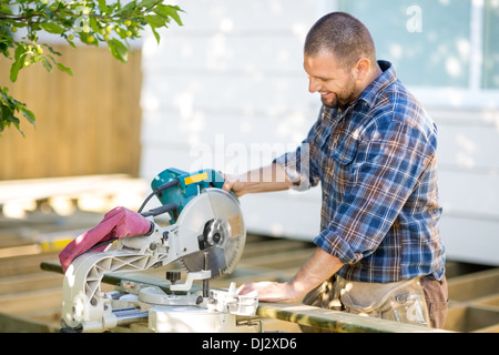 Carpenter Cutting Wood Using Table Saw At Construction Site Stock Photo