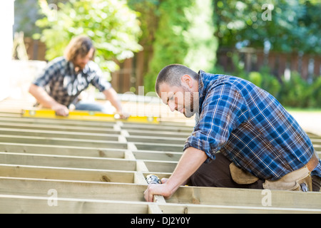 Carpenter Using Drill On Wood At Site Stock Photo