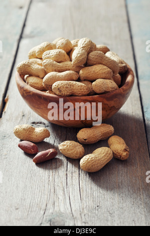 Unpeeled peanuts in bowl on wooden background closeup Stock Photo