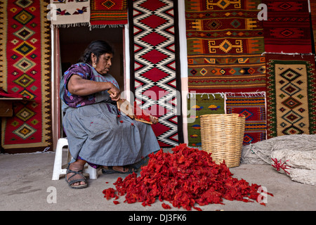 A Zapotec indigenous woman hand cards dyed wool into yarn to be used in weaving traditional carpet in Teotitlan de Valle, Mexico Stock Photo