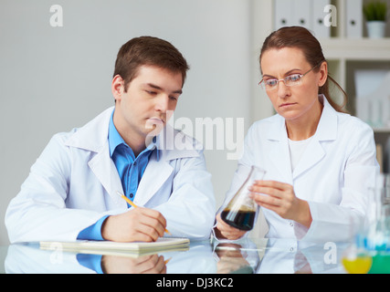 Two scientists looking at glass flask with liquid in laboratory Stock Photo