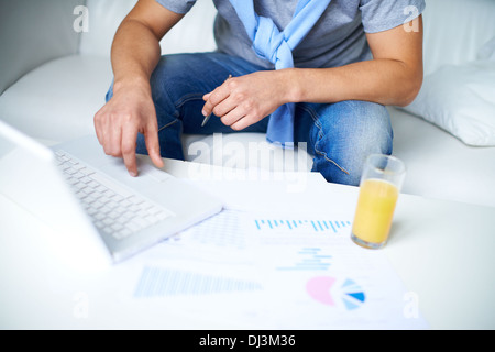 Image of young guy in casual sitting on sofa and using laptop Stock Photo