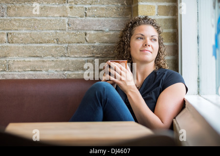 Thoughtful Woman Holding Coffee Mug In Cafe Stock Photo