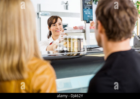 Saleswoman Looking At Customers In Butcher's Shop Stock Photo