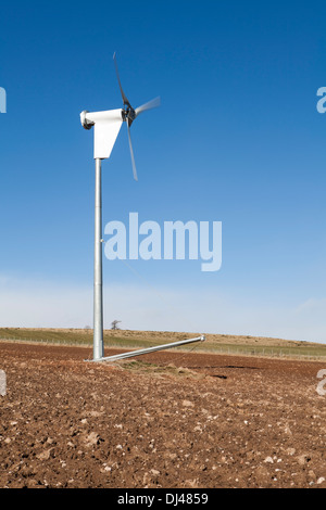 Wind turbine against a bright blue sky on a farm. Stock Photo