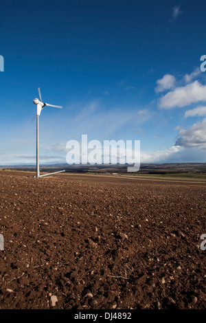 Wind turbine against a bright blue sky on a farm. Stock Photo