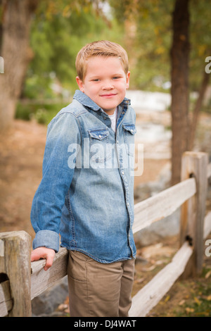 Handsome Young Boy Leaning Against A Fence in the Park. Stock Photo