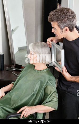 Hairdresser Holding Mirror Behind Senior Woman Stock Photo