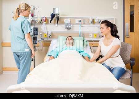 Woman Holding Patient's Hand While Looking At Nurse Stock Photo