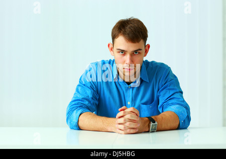 Portait of a young confident businessman sitting at the table in office Stock Photo