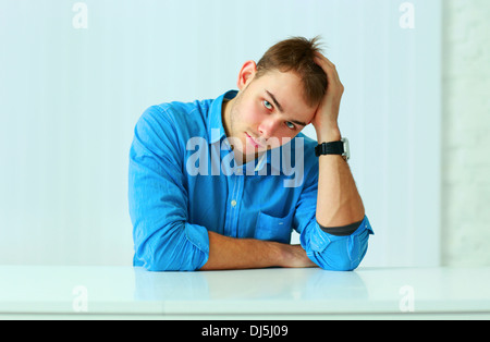 Portait of a young thoughtful businessman sitting at the table in office Stock Photo