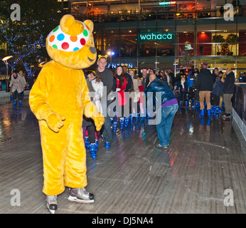 Pudsey Bear at London's Canary Wharf Leading a successful attempt of the longest conga on ice, 353 people, for Children In Need. Stock Photo