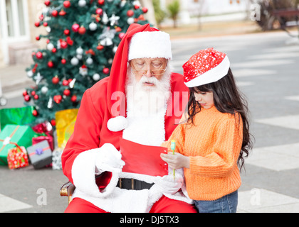 Girl Showing Wish List To Santa Claus Stock Photo