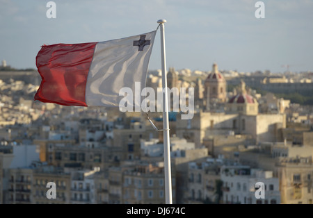 Flag of Malta with George Cross with the old city of Senglea in the background overlooking the Grand Harbour of Valletta Stock Photo