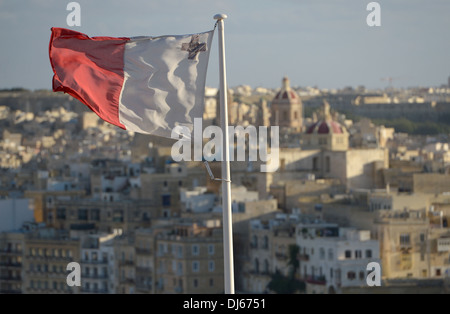 Flag of Malta with George Cross with the old city of Senglea in the background overlooking the Grand Harbour of Valletta Stock Photo