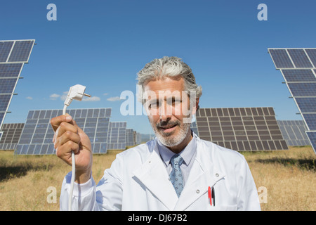 Scientist holding plug to solar panels Stock Photo