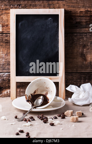 Cup of drunk coffee with blank chalkboard on table with crumbs and crumpled napkin. See series Stock Photo