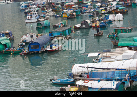 Chinese Man rows past Sampans moored in a Typhoon Shelter, Hong Kong. Stock Photo