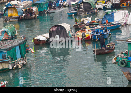 Chinese Man rows past Sampans moored in a Typhoon Shelter, Hong Kong. Stock Photo