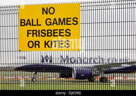 Signs on security fencing at Manchester Airport, UK, with a plane behind. Stock Photo