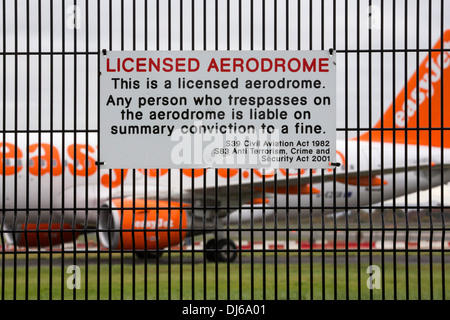 Signs on security fencing at Manchester Airport, UK with a plane behind. Stock Photo