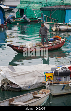 Chinese Man rows across the Typhoon Shelter early in the morning, Causeway Bay, Hong Kong. Stock Photo