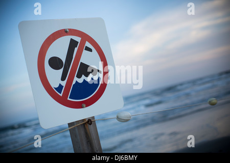 A no swimming sign on a beach at sunset in Galveston, Texas, USA. Stock Photo
