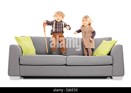 Brother and sister siblings standing and playing on a sofa Stock Photo