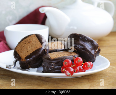 chocolate mini cakes decorated with currants on a white plate Stock Photo