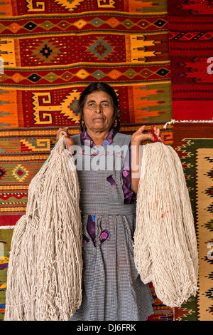 A Zapotec indigenous woman holds natural yarn after spinning it for use in weaving traditional carpets in Teotitlan, Mexico Stock Photo