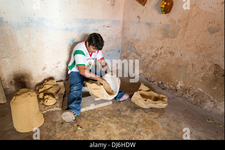 Coating the Mold. A potter works in a small concrete room coating the inside of molds to create the large pieces of pottery Stock Photo