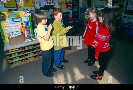 Two Girls & Two Boys In Classroom Talking Stock Photo