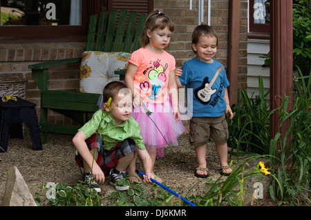 Five Year Old Brother , Three Year Old Sister and Two Year Old Cousin Playing on Porch of Suburban Home Stock Photo