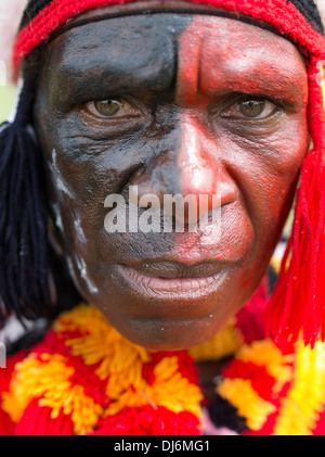 Tribal man with red and black painted face ¥ from Goroka region,  at Goroka Show Singsing Papua New Guinea Stock Photo