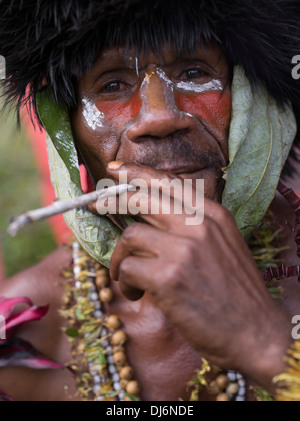 Tribal man smoking hand rolled cigarette  - Goroka Show, Papua New Guinea Stock Photo