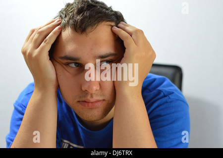 feeling fed up and grumpy, a close up of a young mans face, does he have a headache? is he frustrated and bored with life? Stock Photo
