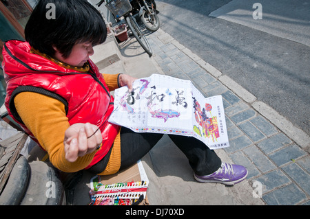 Woman doing cross-stitch on street in Beijing, China Stock Photo