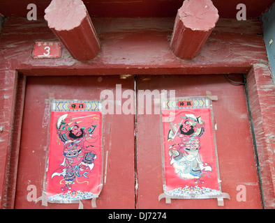 Red door with guardian posters in Menlou hutong, Beijing, China Stock Photo