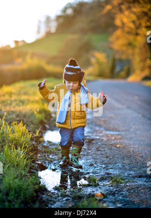 A small boy out on a cold evening finds a puddle UK Stock Photo