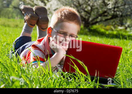 boy using his laptop outdoor in park on grass Stock Photo