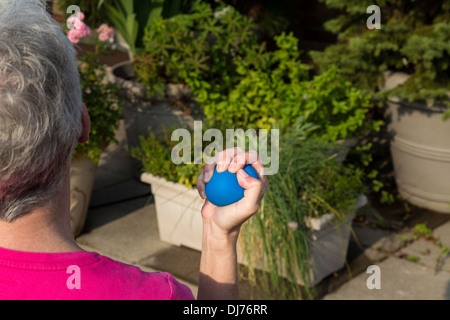Senior Woman flexing stress ball, USA Stock Photo