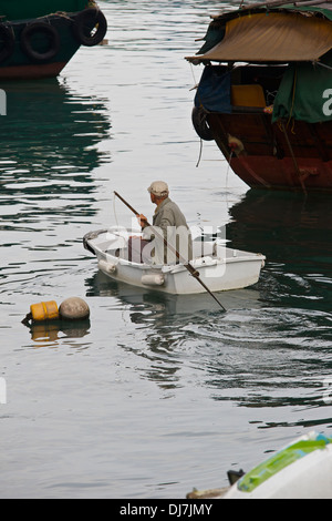 Old Chinese Man rows across the Causeway Bay Typhoon Shelter, Hong Kong. Stock Photo