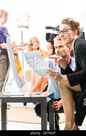 Team or Director discussing during a break the scene direction on set of a commercial video production or reportage at a screen Stock Photo